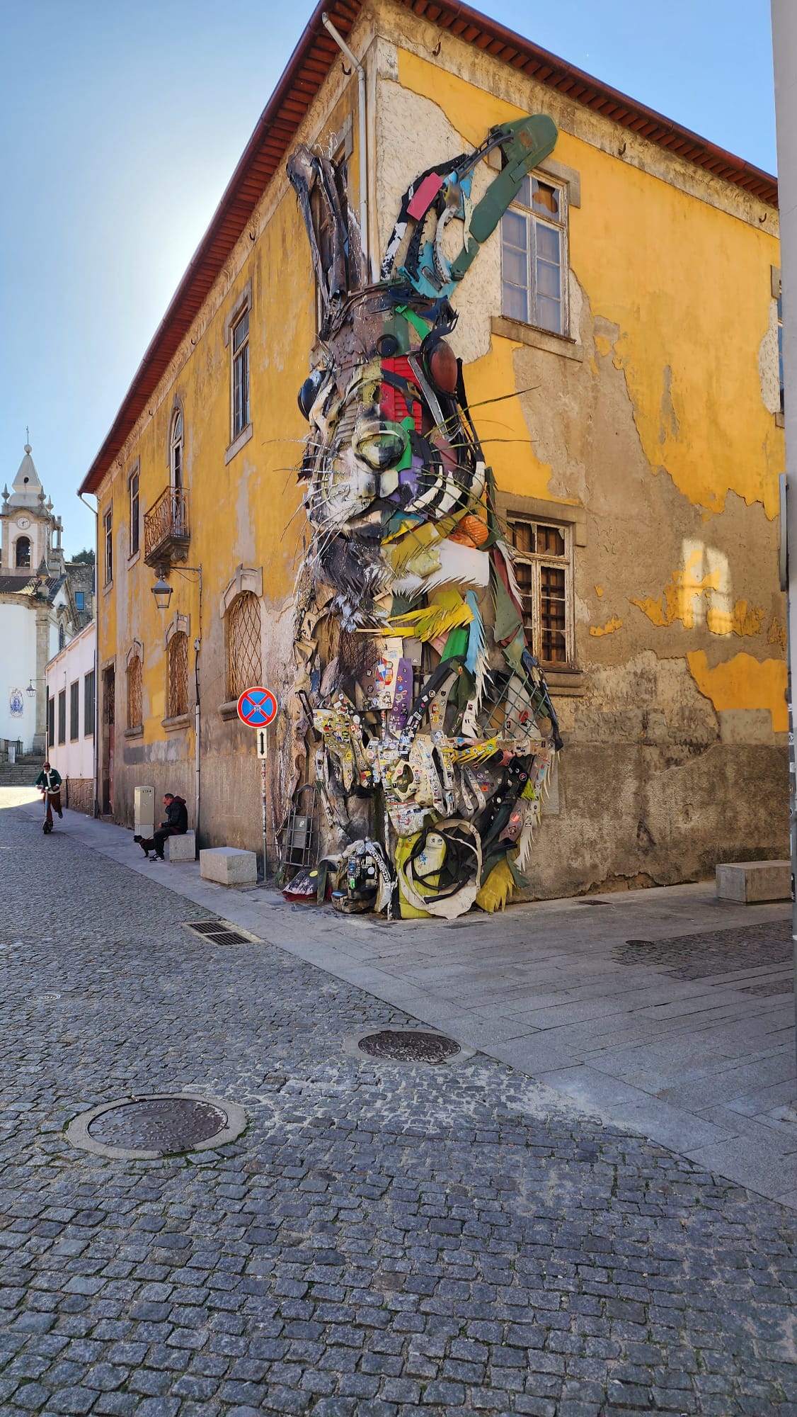 Colorful street art installation on a narrow cobblestone street in Portugal