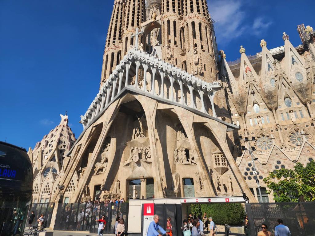 Exterior view of the Sagrada Família, a famous basilica in Barcelona, showcasing its unique architectural design and intricate details under a clear blue sky.